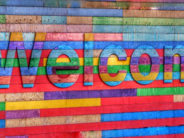 A colourful wall made of wood, with the word Welcome.