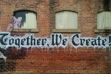 Image of wall with words "together we create" written on it