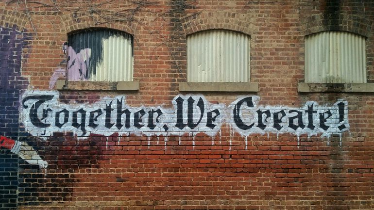 Image of wall with words "together we create" written on it