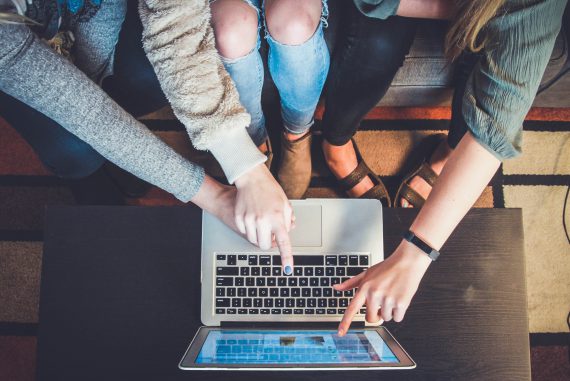 3 students pointing toward computer screen