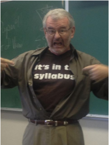 A Professor points to to his "It's in the syllabus" t-shirt. 