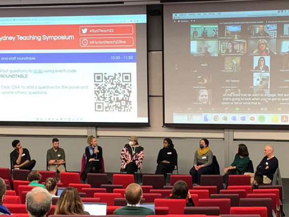 Eight roundtable participants sitting at the front of a lecture theatre