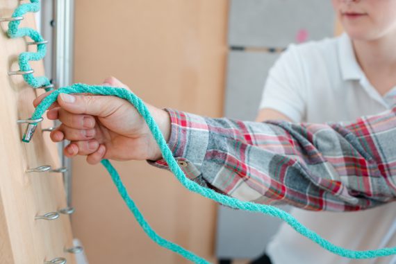 Person in occupational therapy with therapist training his dexterity at the rope board