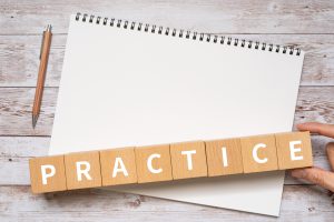 Blocks spelling the word "practice" across a blank notepad. 