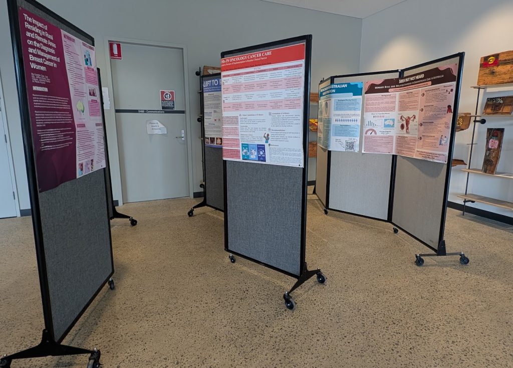 Student research posters displayed on portable boards in an exhibition space.