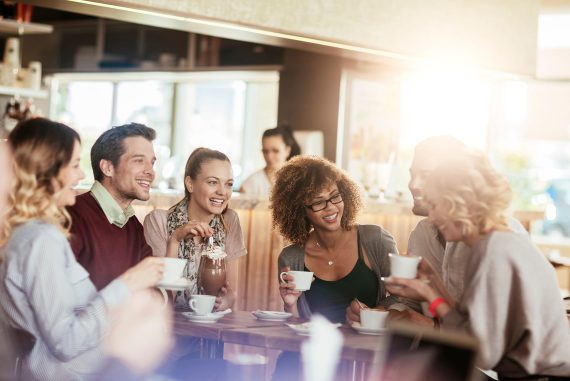 Diverse group of young people talking and having a coffee at a cafe
