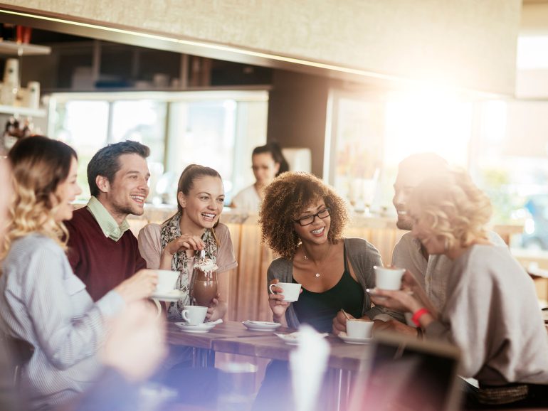 Diverse group of young people talking and having a coffee at a cafe