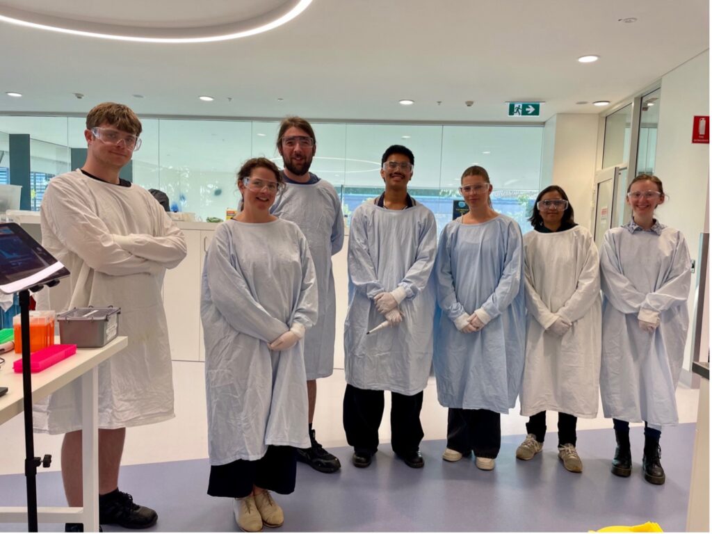 Half of the GEGE3004 teaching team, in a lab environment wearing lab coats